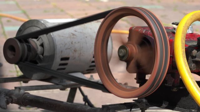 Rusty and old water pump motor working, Rotating pulley and belt on air pump machine