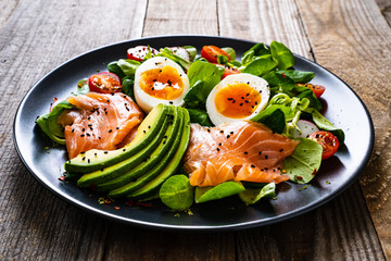 Salmon salad - smoked salmon boiled egg and vegetables on wooden background
