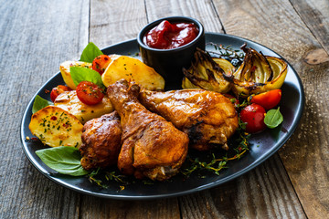 Barbecue chicken drumsticks with vegetables on wooden table
