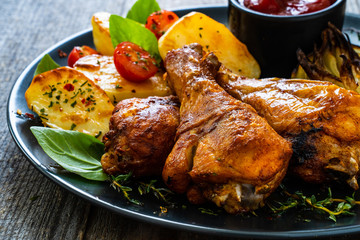 Barbecue chicken drumsticks with vegetables on wooden table
