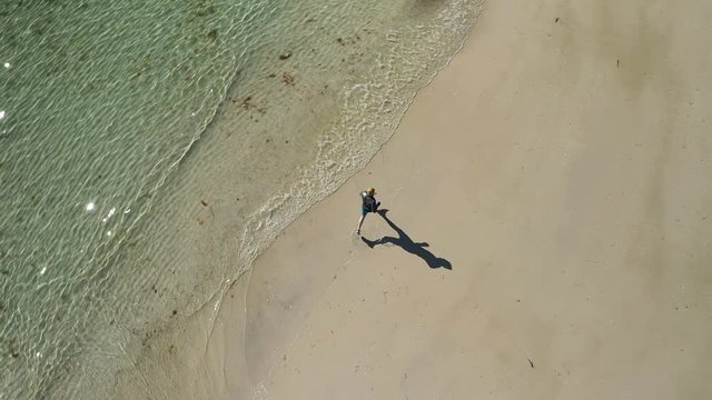 aerial view of man jogging on tropical sandy beach near sea. Man running on tropical beach. Surrounded by mountains. Located north of norway, lofoten islands at haukland beach