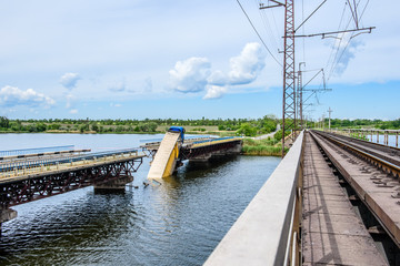 Destruction of bridge structures across the river with the collapse of sections into the water