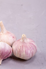 Three heads of garlic close-up on a gray background