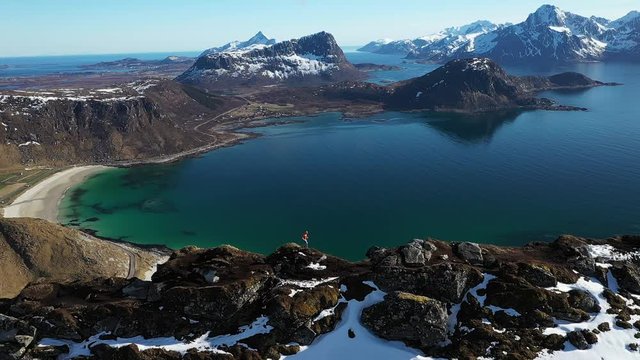 aerial video of trail runner man running on the ridge of mountain with incredible view over beach and mountains. Located norway, lofoten islands at haukland beach and mannen mountain.