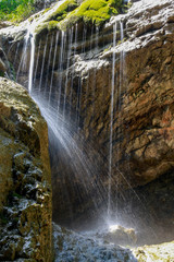 Wasserfäden laufen von Felsen und glitzern im Sonnenlicht