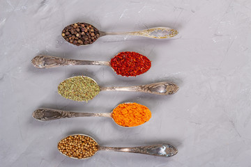 Dry spices of different colors in teaspoons. Top view