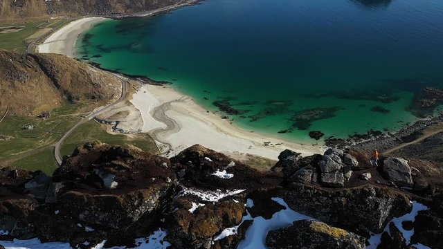 aerial video of trail runner man running on the ridge of mountain with incredible view over beach and mountains. Located norway, lofoten islands at haukland beach and mannen mountain.