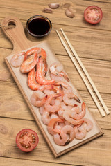Tiger prawns and shrimp, halves of tomato and soy sauce on table.