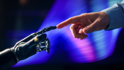 Humanoid Robot Arm Touches Human Hand Connecting Fingers. Humanity and Artificial Intelligence...