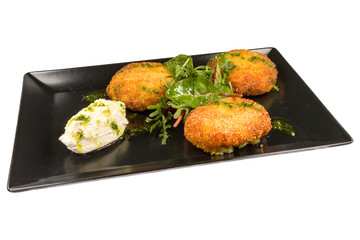 Gourmet fried zucchini balls with arugula,  and cheese with basil, on a black plate, isolated on white background