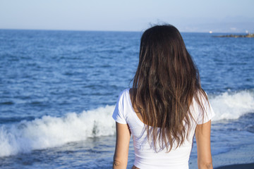Girl dressed in white with the sea on her back