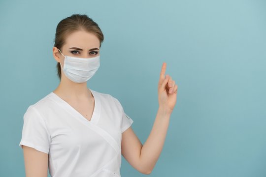 masked female doctor points to item or list on blue background