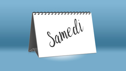 Ein Kalender für den Schreibtisch zeigt den französischen Wochentag Samedi (Samstag in deutscher Sprache)