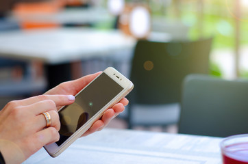 female hand holding smart phone in summer terrace cafe, close up
