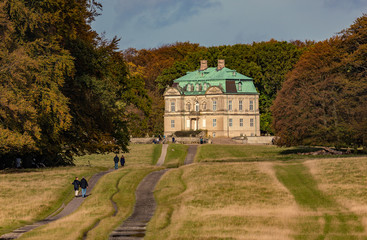 Couples strolling towards the 18th century royal hermitage hunting lodge in public parc of Dyrehaven north of Copenhagen