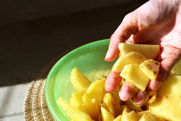 Sliced potato in a hand. Flavored potato slices in a hand. Sliced Potatoes. Chopped potatoes in a bowl