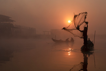 fisherman with sunrise on boat over river © Mai