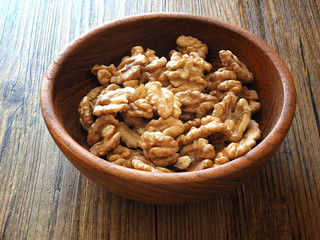 Walnuts in a wooden bowl on a wooden table