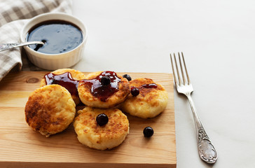 Breakfast in the morning. Cottage cheese pancakes with jam  on wooden background. Russian, Ukrainian cuisine.