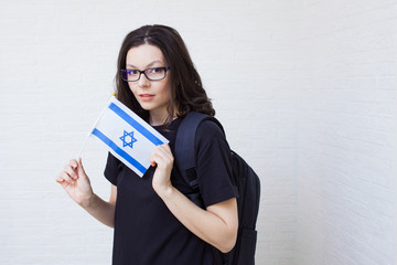 young woman with glasses holds the flag of Israel.
