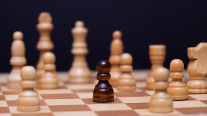 Chess, a lot of chess pieces on the Board. The white pieces surrounded the black pawn.