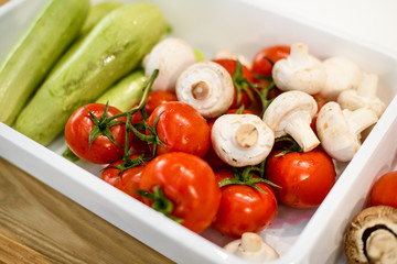 Close-up on white plastic box with vegetables and mushrooms in it