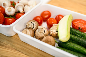 Close-up of white box with fresh vegetables stand on table.