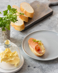 Bruschetta with smoked salmon and butter on concrete table with bread, butter and herbs. Delicious snack or appetizer.