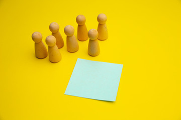 Teamwork, teambuilding mockup, company structure. Wooden figures stands near blue sticky note, place for text.