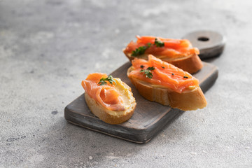 Three toasts with smoked salmon and butter on cutting board. Delicious snack for keto diet.