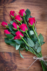 Bunch of red roses tied with string on a wooden background