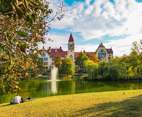 Lake in center of Wroclaw Tolpa Park with fountain in center with faculty of architecture of Wroclaw University - obrazy, fototapety, plakaty
