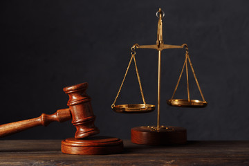 Law and justice concept. Lawyers desk. Judge's gavel, scales, wooden table. Dark gray bokeh...