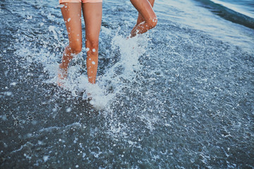 Fototapeta premium Girls stand in the water by the sea.