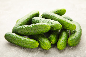 Many harvest cucumbers on the grey concrete background