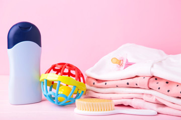 Baby clothes with a shower accessories on a pink background
