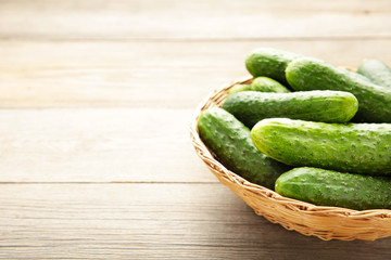 Fresh cucumbers in basket on grey background.