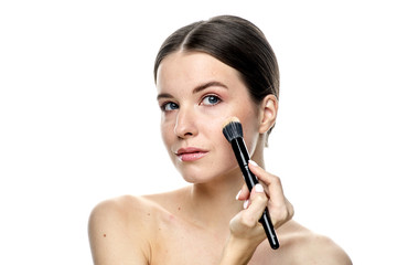 close-up portrait of a girl without makeup with clean skin with a makeup brush in hand, isolated on a white background