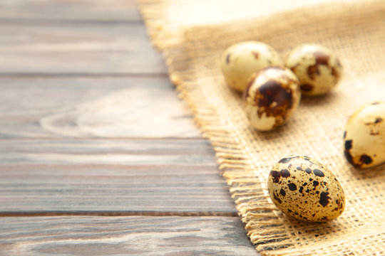 Many quail eggs with sackcloth on brown background
