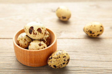 Fresh quail eggs in bowl on grey wooden background