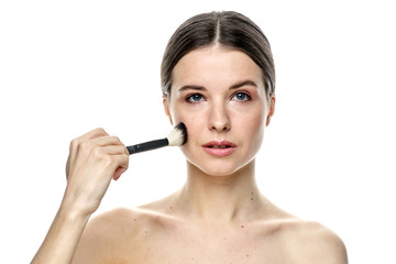 close-up portrait of a girl without makeup with clean skin with a makeup brush in hand, isolated on...