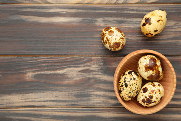 Fresh quail eggs in bowl on brown background