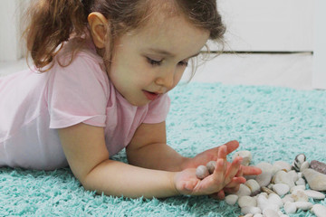 A child plays with pebbles. Concept of development and training of a child at home. A favorable...
