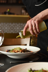 Chef drizzling oil over salad