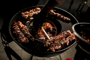 View on round barbecue grill with pieces of fried meat.