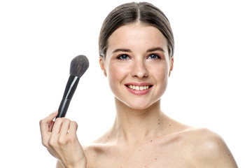 close-up portrait of a girl without makeup with clean skin with a makeup brush in hand, isolated on a white background