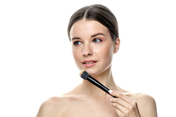 Fototapeta premium close-up portrait of a girl without makeup with clean skin with a makeup brush in hand, isolated on a white background