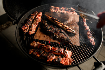 View on grill with pieces of fried meat and fish in center