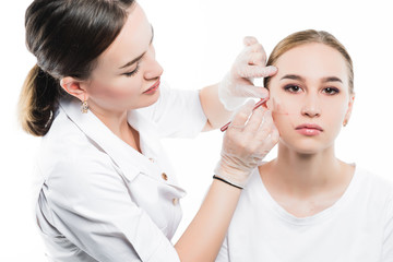 A cosmetologist examines the patient face and plans to perform a series of cosmetic procedures