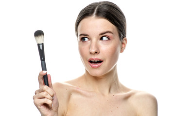 close-up portrait of a girl without makeup with clean skin with a makeup brush in hand, isolated on...